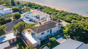 An aerial view of a coastal residential area with houses, a beach, and a body of water.