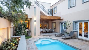 A modern outdoor pool area with a dining setup and lounge chairs.