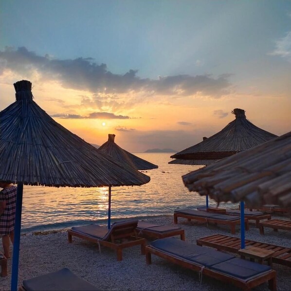 Privatstrand, schwarzer Sandstrand, Liegestühle, Sonnenschirme