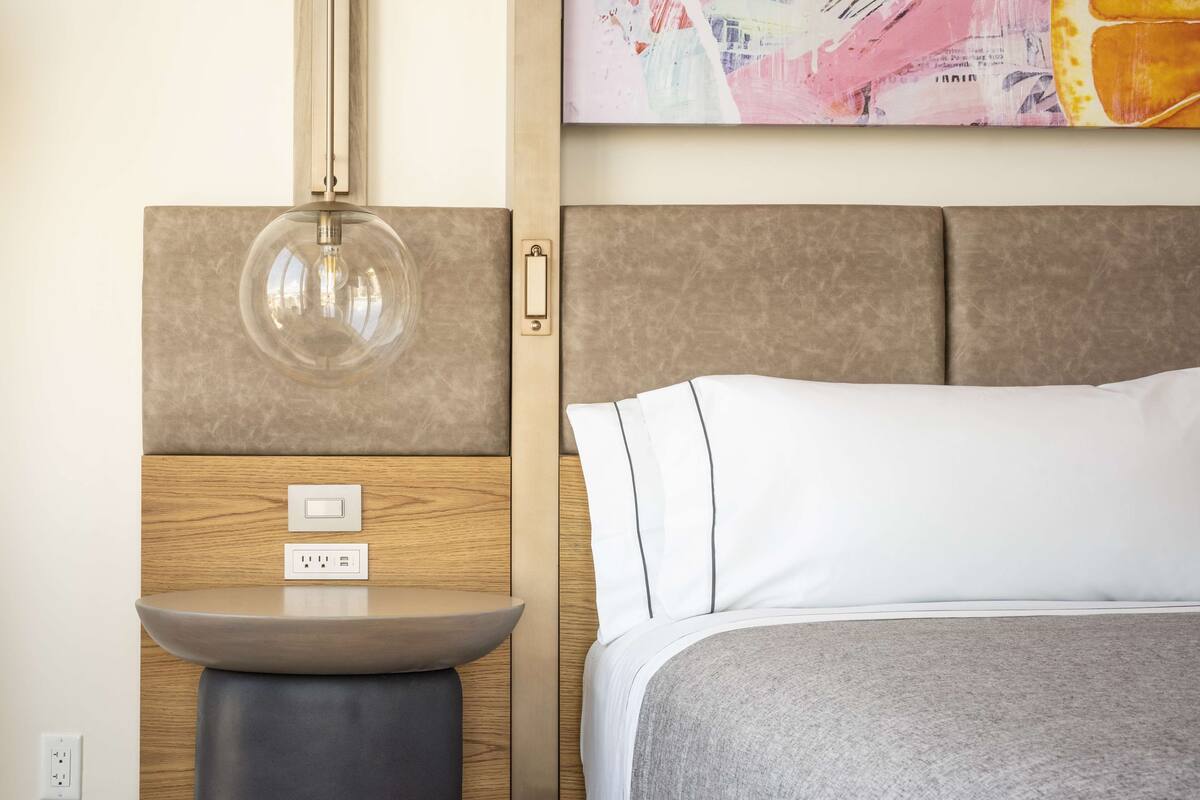 Ein modernes Schlafzimmer mit Bett, Nachttisch und Wandlampe.