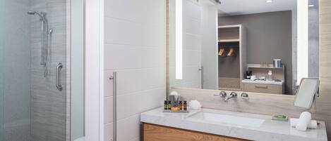A modern bathroom with a glass shower enclosure, a wooden vanity, and a large mirror.