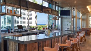 Eine moderne Bar mit einer großen Barinsel, Barhocker und Blick auf den Ozean.