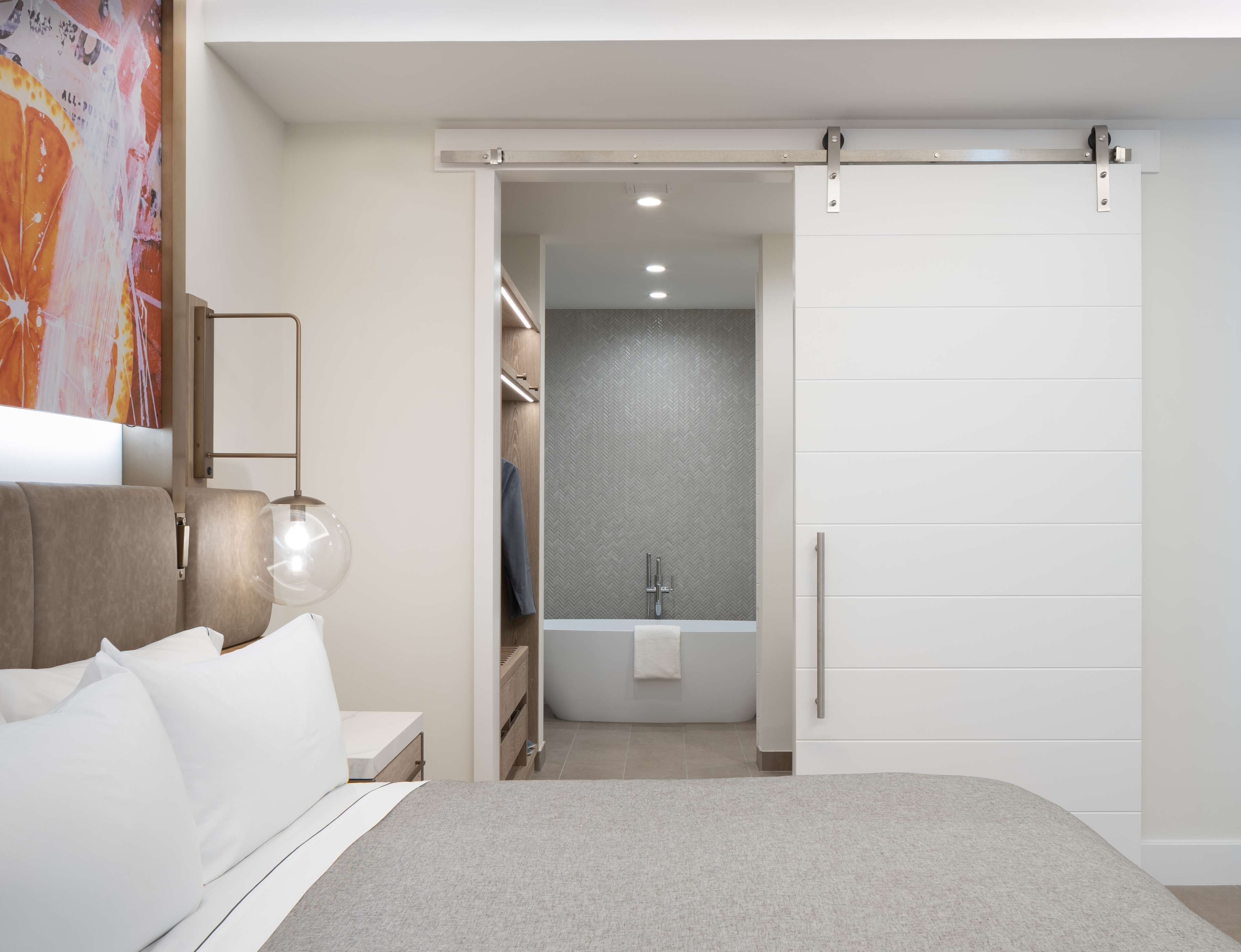 A modern bedroom with a bed, bedside table, and a large window.