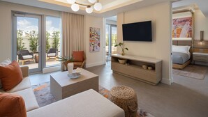 Ein modernes Wohnzimmer mit Sofa, Couchtisch und Fernseher. Ein Schiebetürfenster führt zu einem Außenbereich mit Sitzgelegenheiten.