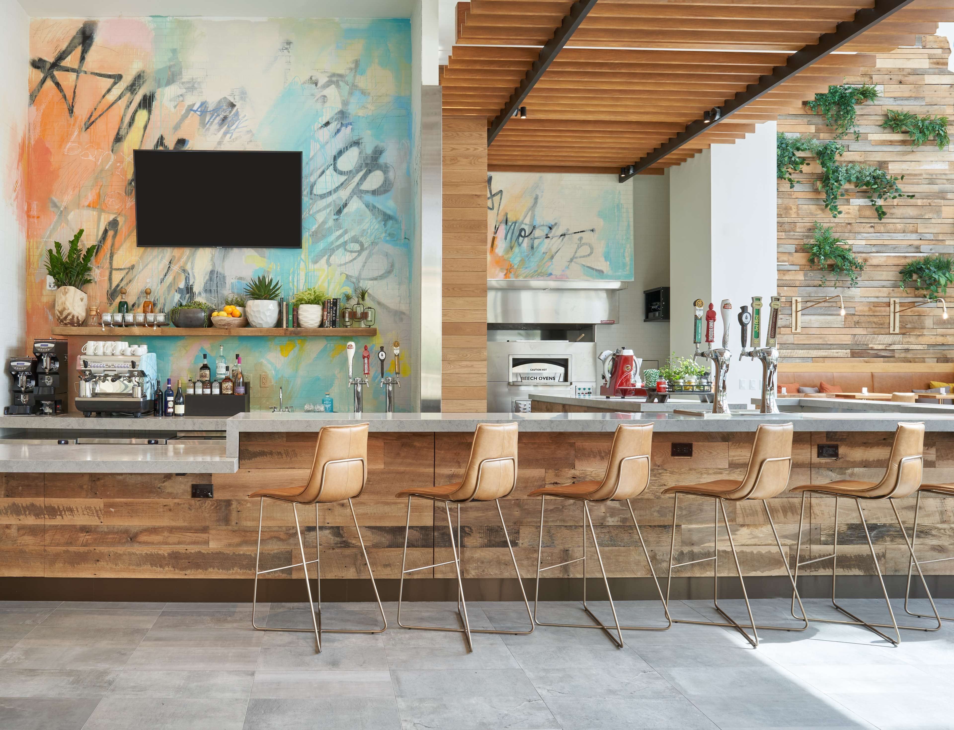 Une cuisine moderne avec un coin bar, des éléments décoratifs en bois et un grand tableau abstrait.