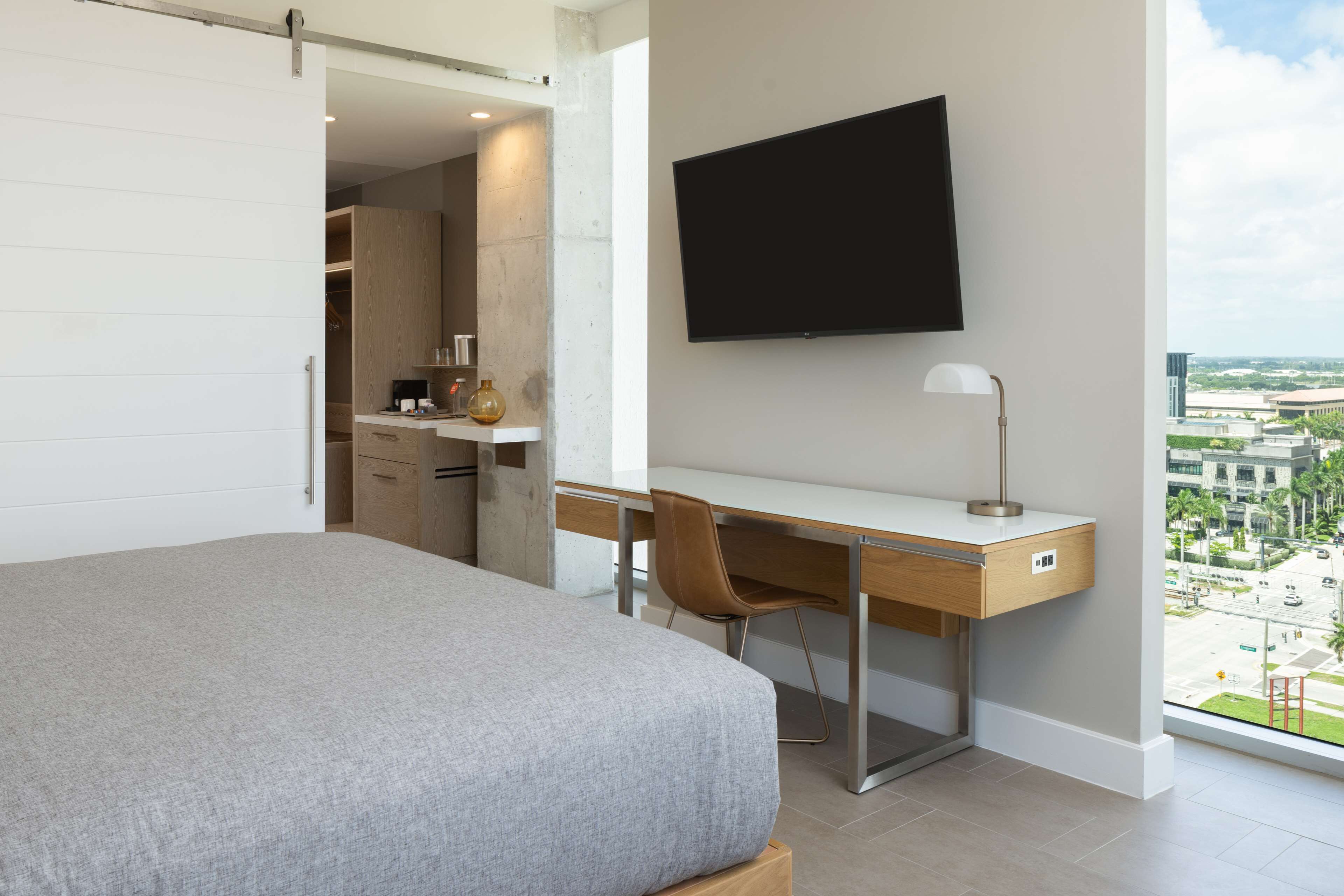 Un dormitorio moderno con una cama grande, un escritorio y un televisor.