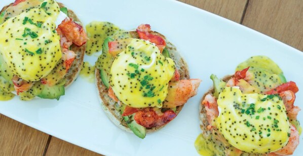 Ein weißer Teller mit drei Portionen eines Fischgerichts, bedeckt mit Sauce Hollandaise und garniert mit Schnittlauch.