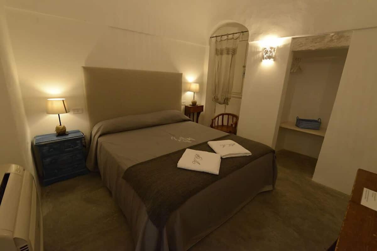 A bedroom with a bed, bedside tables, a wardrobe, and a window with a curtain.