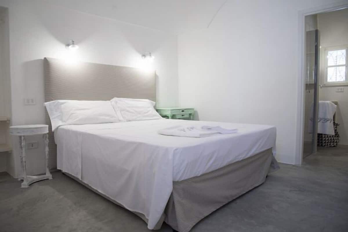 A bedroom with a bed, bedside table, and a nightstand.