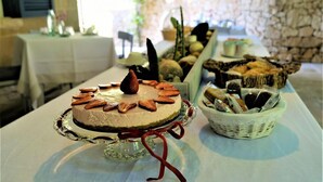Ein Desserttisch mit verschiedenen Kuchen und Gebäck vor einer Steinsäule und einer weißen Tischdecke.