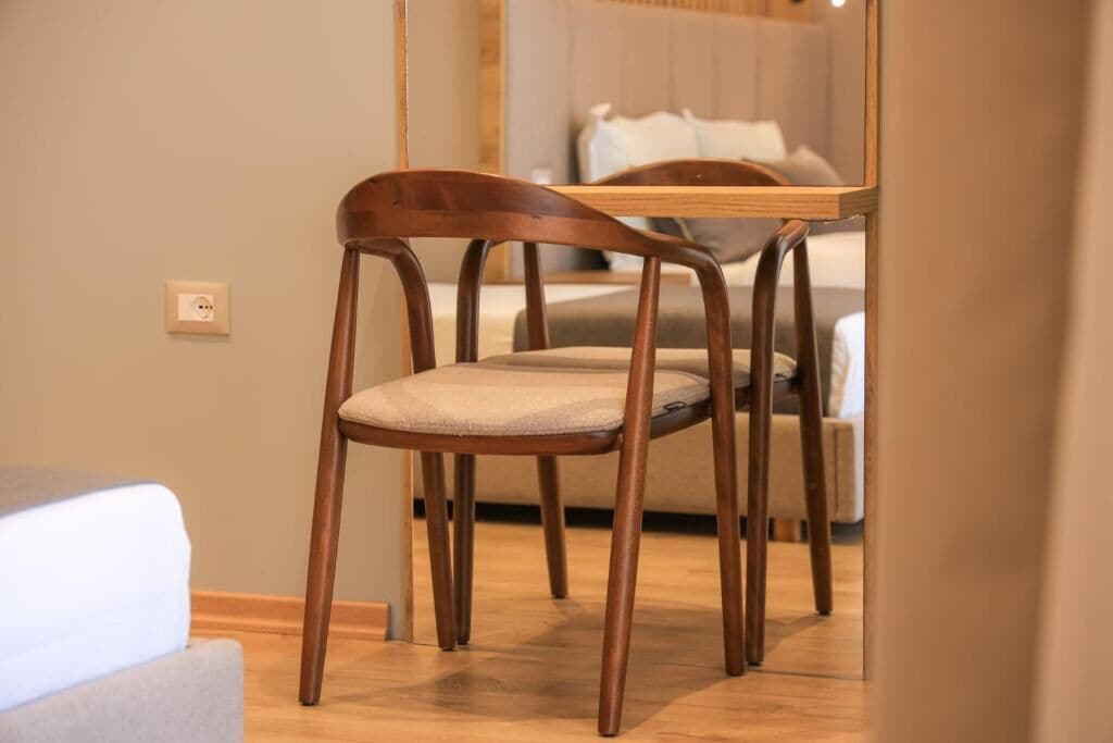 A wooden chair with a cushioned seat and backrest, positioned in front of a wooden table.