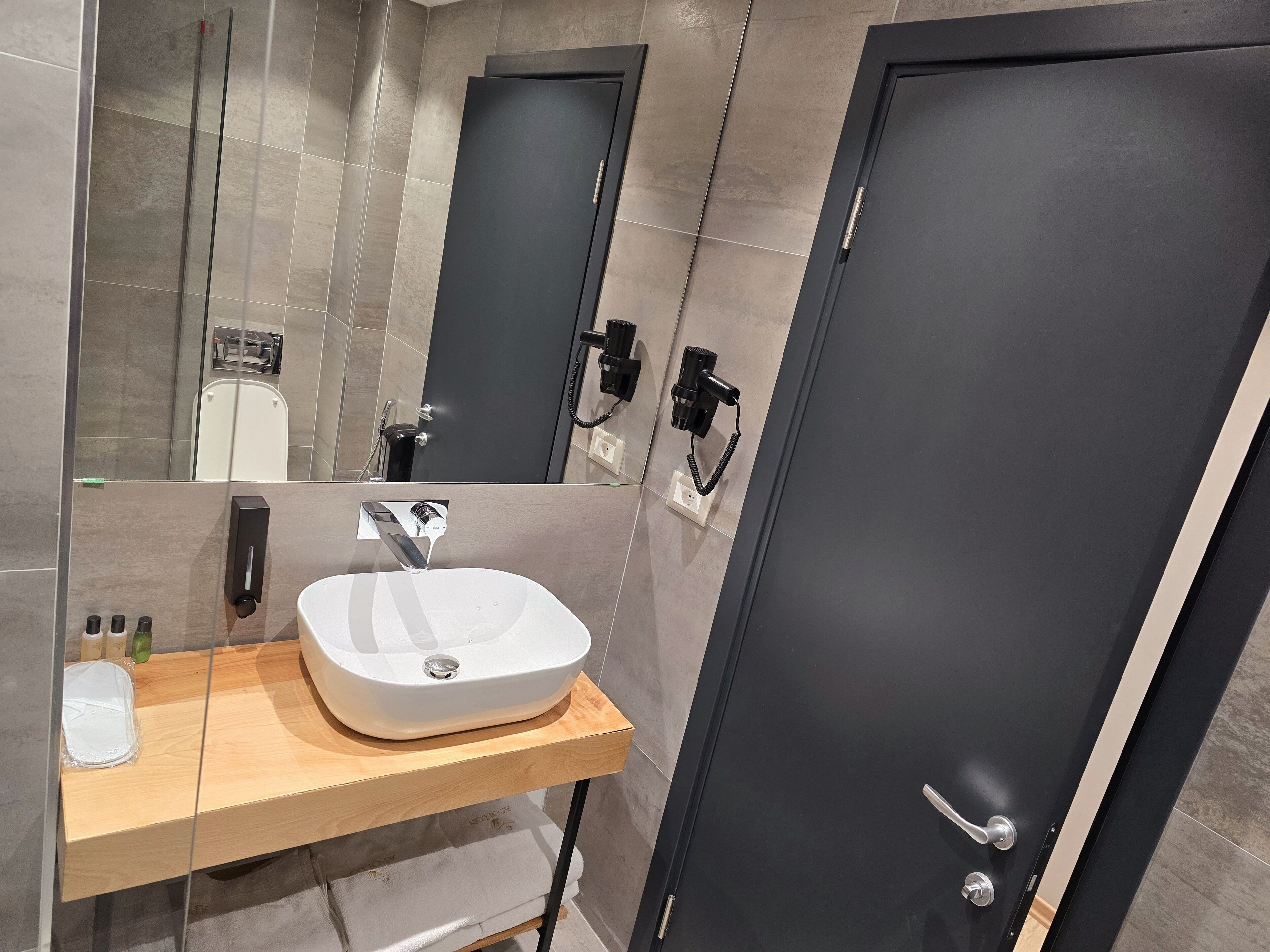 Une salle de bain moderne avec un lavabo blanc, un miroir et une douche.