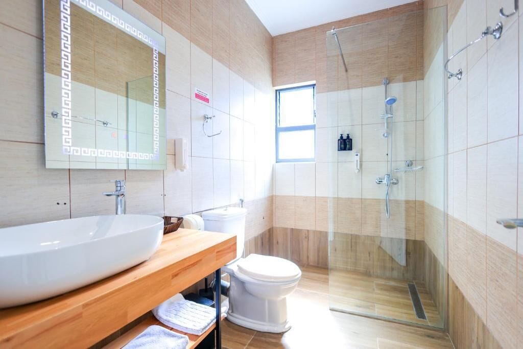 A modern bathroom with a large sink, mirror, and glass-enclosed shower.