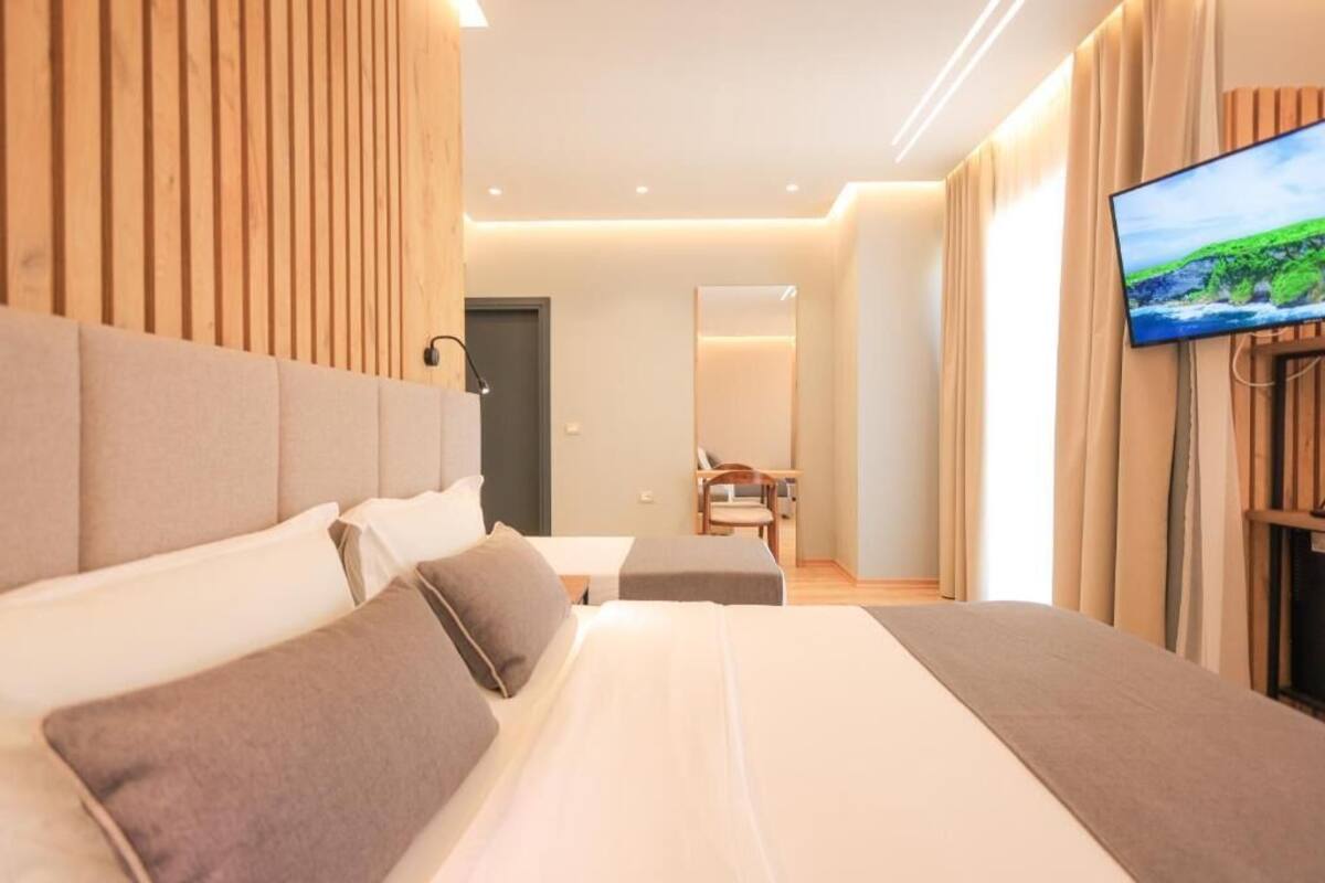 A modern hotel room with a large bed, a television, and a wooden headboard.