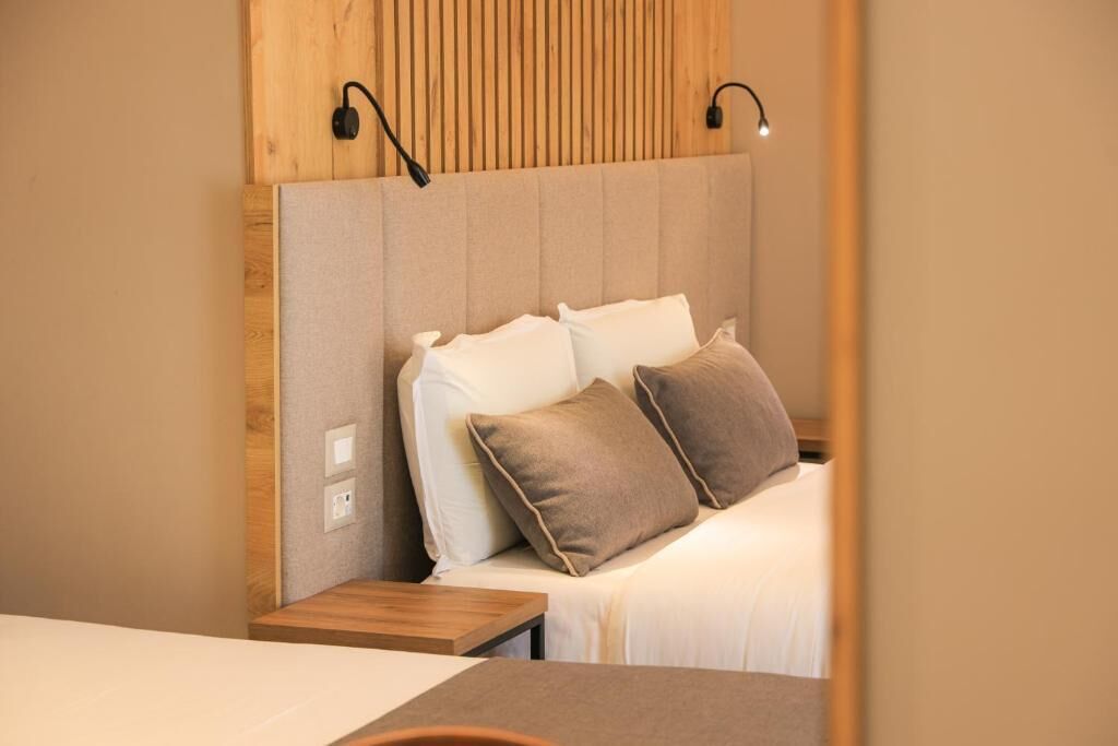 A neatly arranged hotel room with a bed, bedside tables, and a wooden headboard.