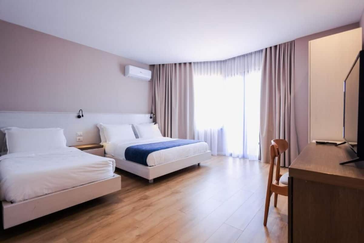 A hotel room with two beds, a desk, and a chair.