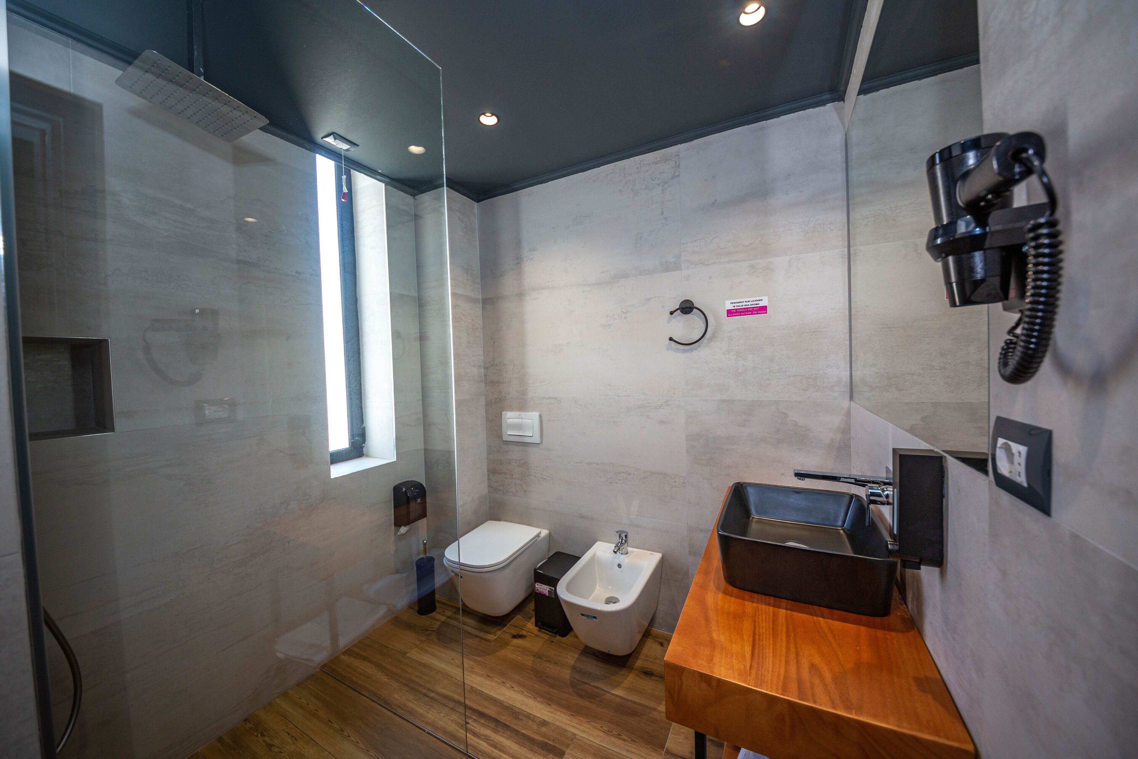 Un baño moderno con tocador de madera, bidé y teléfono.