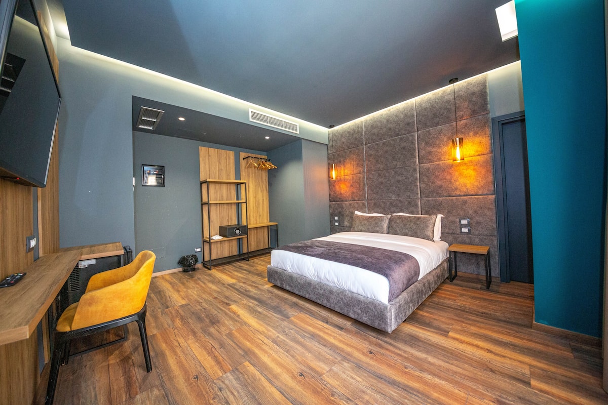 A modern bedroom with a large bed, a desk, and a chair.