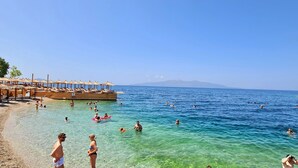 A beach with clear water, umbrellas, and lounge chairs. - Hotel Apollon Saranda (Sarandë)