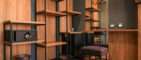 A modern, compact room with built-in wooden shelving, a small seating area, and a compact kitchenette.