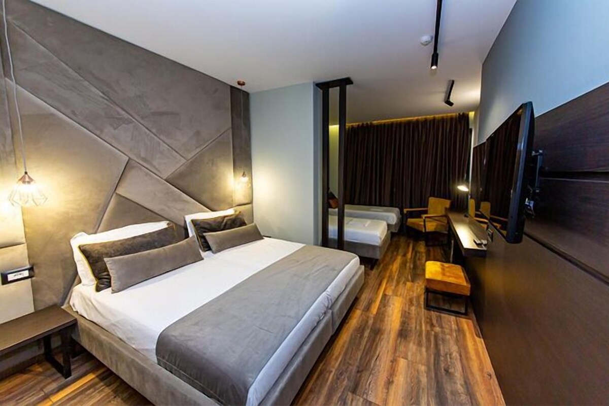A modern hotel room with a large bed, a desk, and a television.