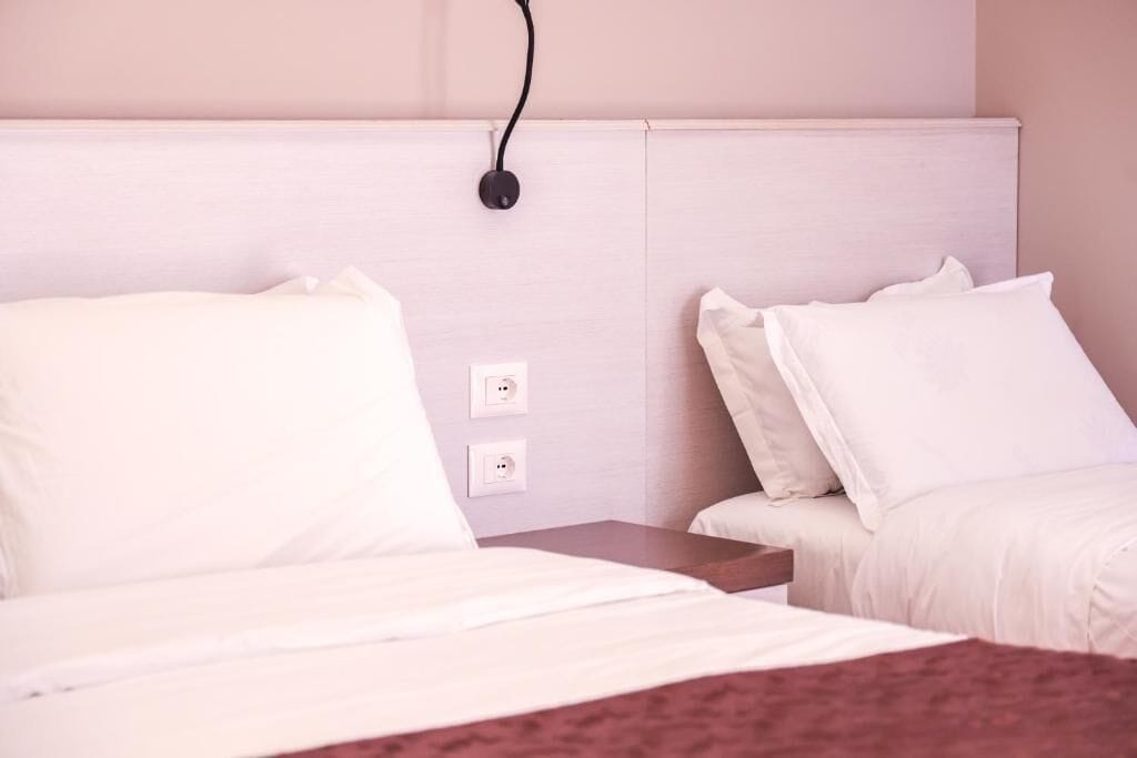 Et hotelværelse med to senge, et træhovedgærde og en stikkontakt.