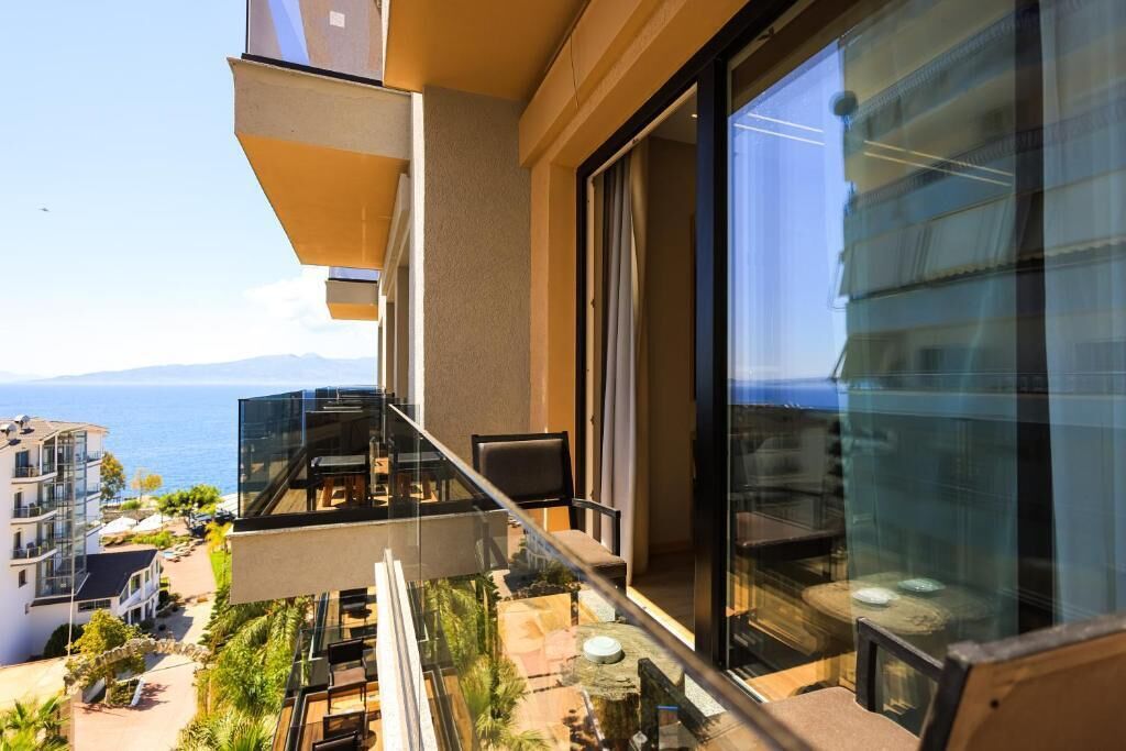 Een modern balkon met glazen balustrade, uitkijkend op een kustgebied.