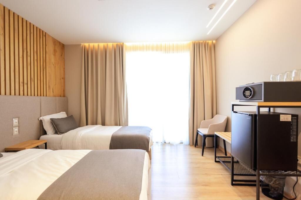 Une chambre d’hôtel avec deux lits, un bureau, une chaise et un téléviseur.