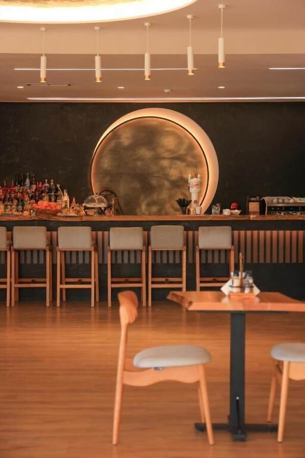 A bar area with a round mirror, wooden chairs, and a table with stools. - Hotel Apollon Saranda (Sarandë)