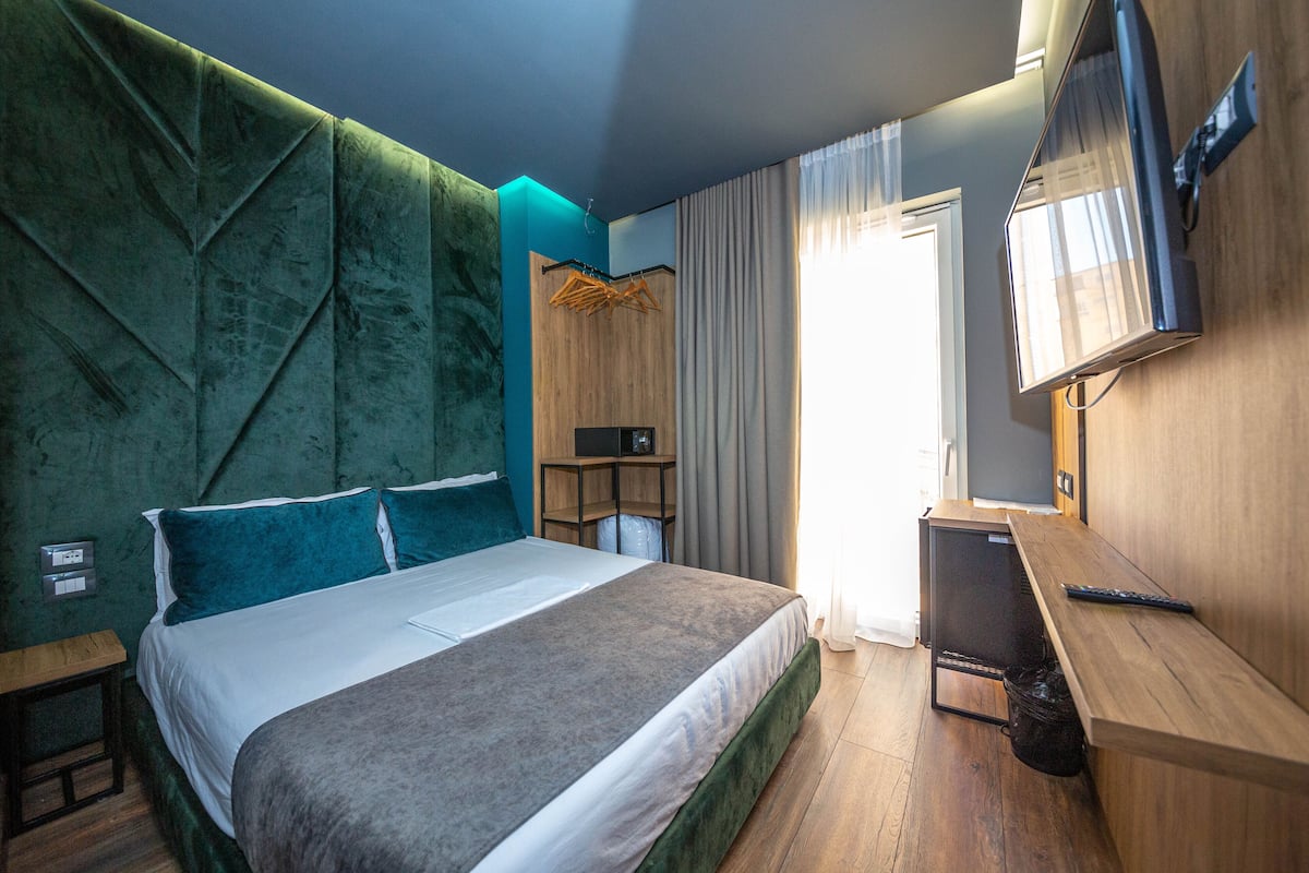 A modern hotel room with a large bed, a wooden desk, and a television.