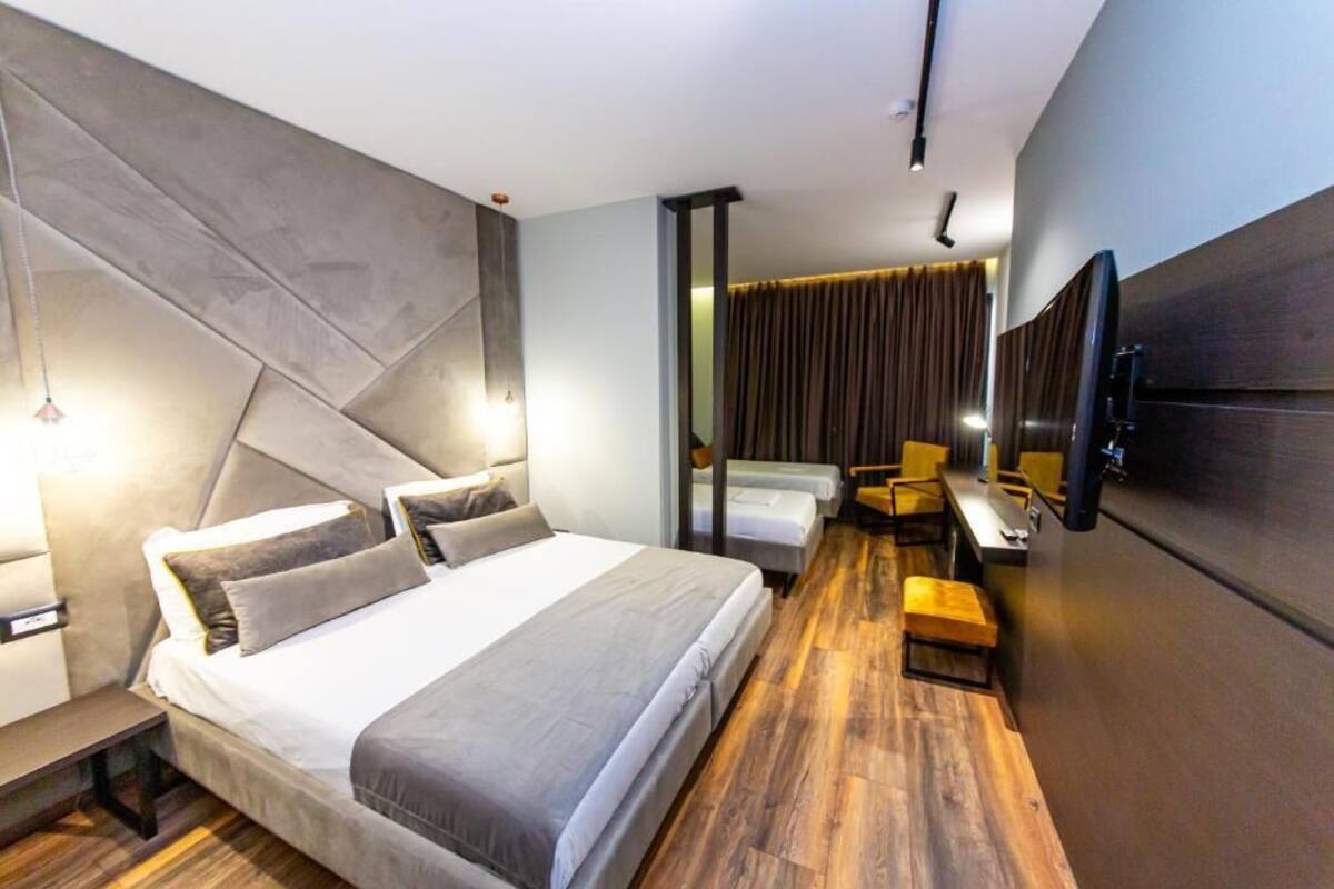 A modern hotel room with a large bed, a desk, and a seating area.