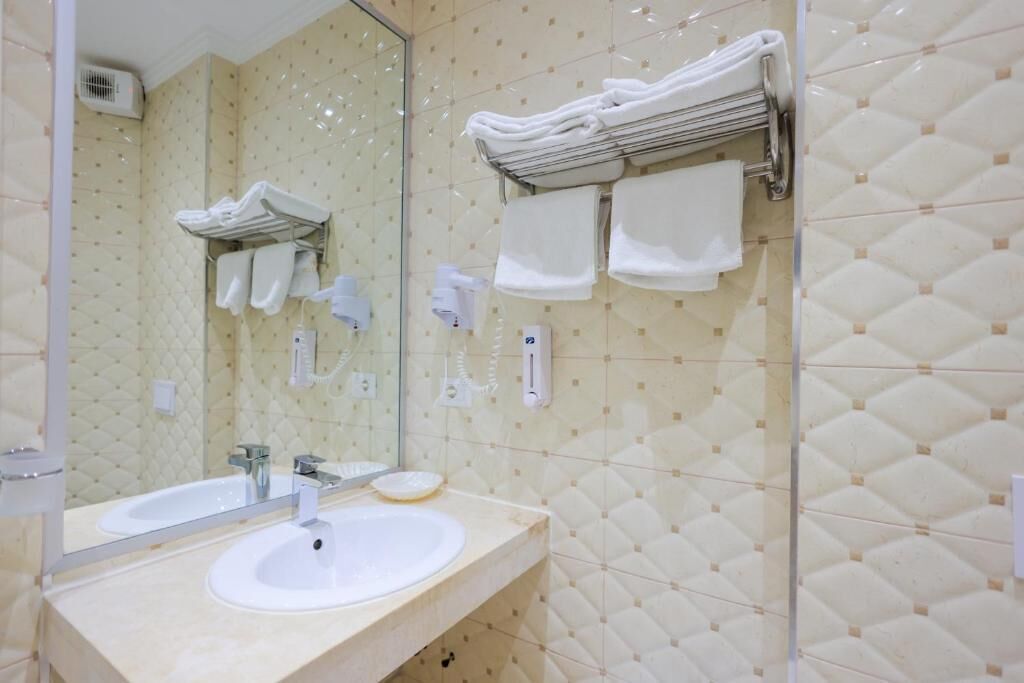 A bathroom with two sinks, a large mirror, and a towel rack with folded towels.
