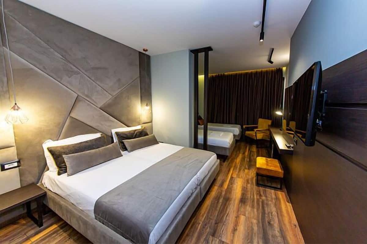 A modern hotel room with a large bed, a desk, and a television.