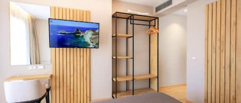 A modern bedroom with a bed, a desk, a TV, and a wooden wardrobe.