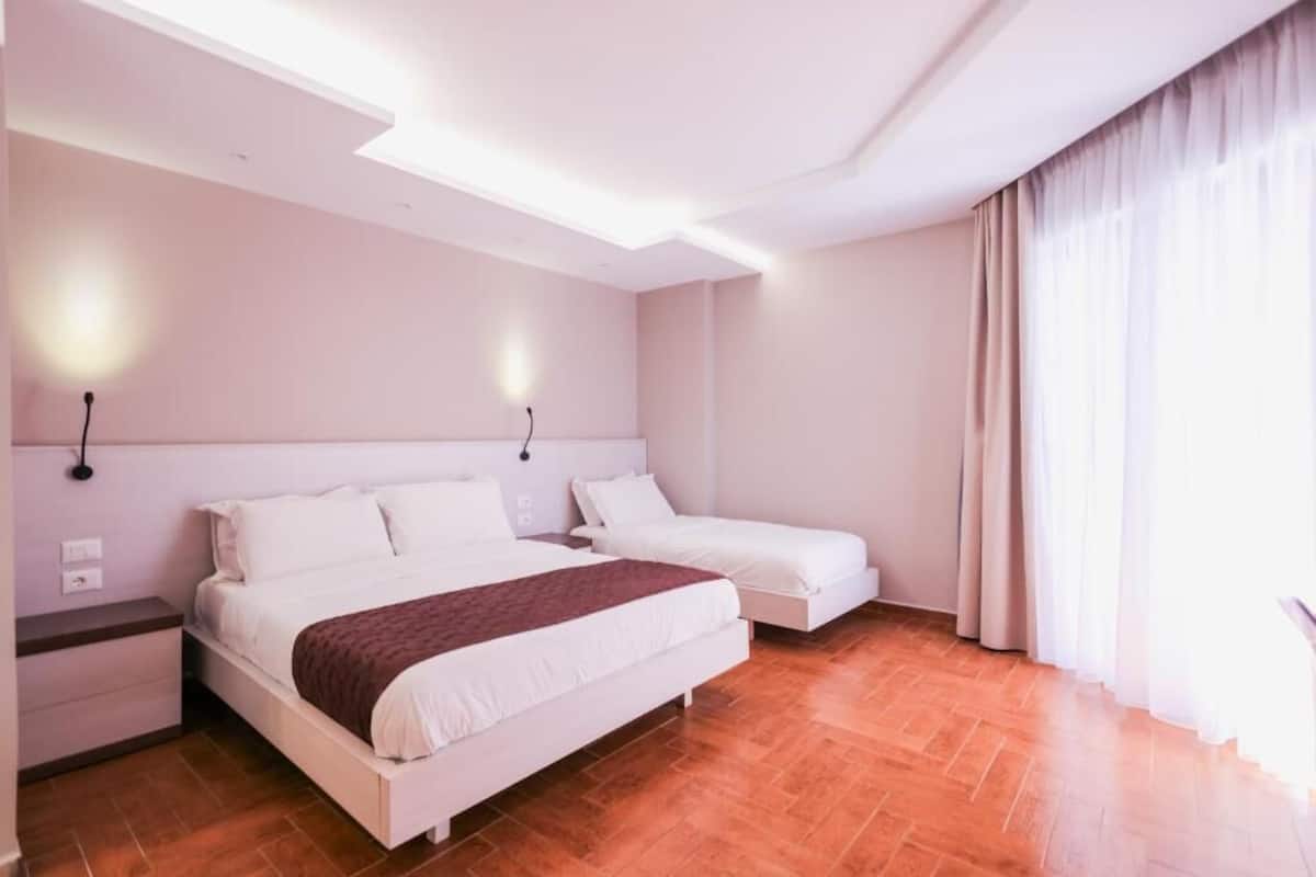 A modern hotel room with a large bed, a smaller bed, and a nightstand.