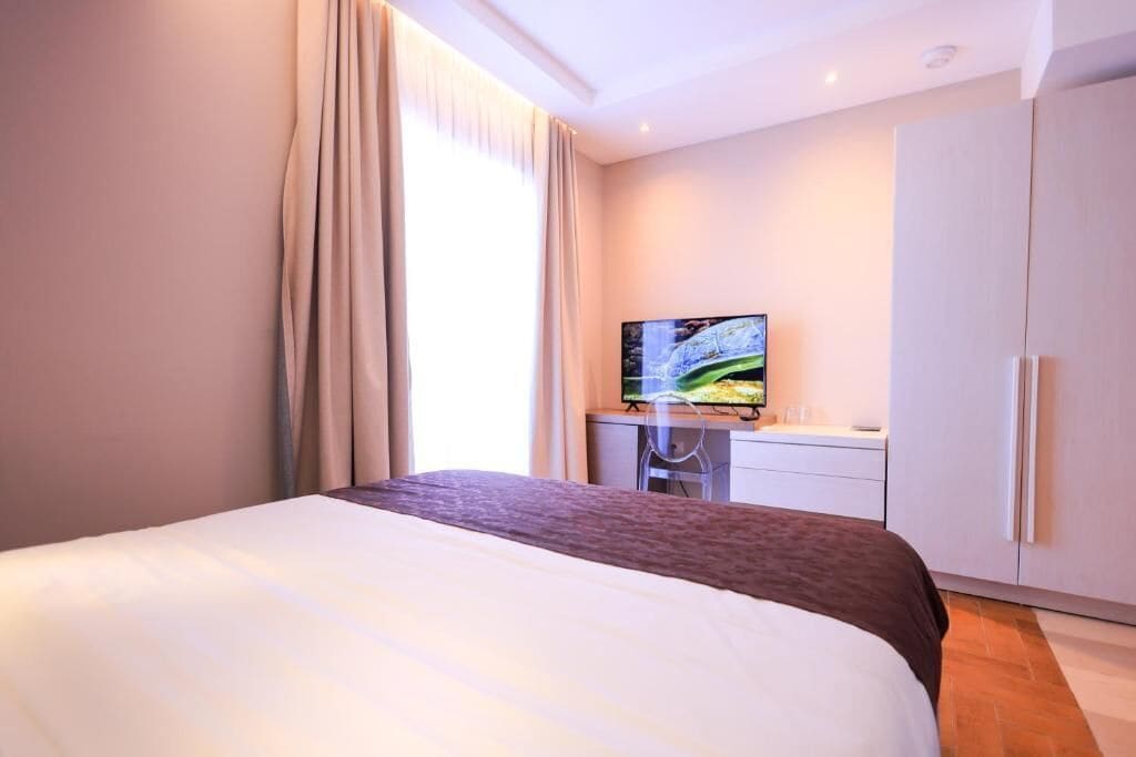 Ein Hotelzimmer mit einem großen Bett, einem Fernseher auf einem Schreibtisch und einem Kleiderschrank.