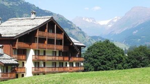 Un chalet en bois doté de plusieurs balcons, situé dans un cadre montagneux.