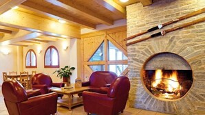 A cozy room with a stone fireplace, leather sofas, and wooden beams. - 50m from ski slopes, swimming pool, balcony, tv, 32m², Val Cenis (Lanslebourg-Mont-Cenis)