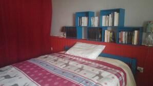 Une chambre à coucher avec un lit, une bibliothèque et un mur rouge.