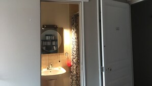 Une salle de bain avec un lavabo, un miroir et un rideau de douche.