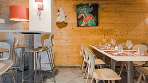 Ein Essbereich mit Holzwand, einem Tisch für vier Personen und modernen Stühlen.