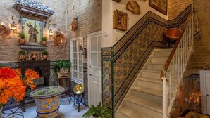 Una imponente escalera con detalles intrincados en azulejos, un muro tradicional revestido de cerámica y un nicho decorativo con techo de azulejos y puerta de bronce.