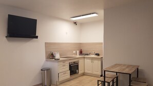 A compact kitchen with a built-in oven, a sink, and a small dining area with stools.