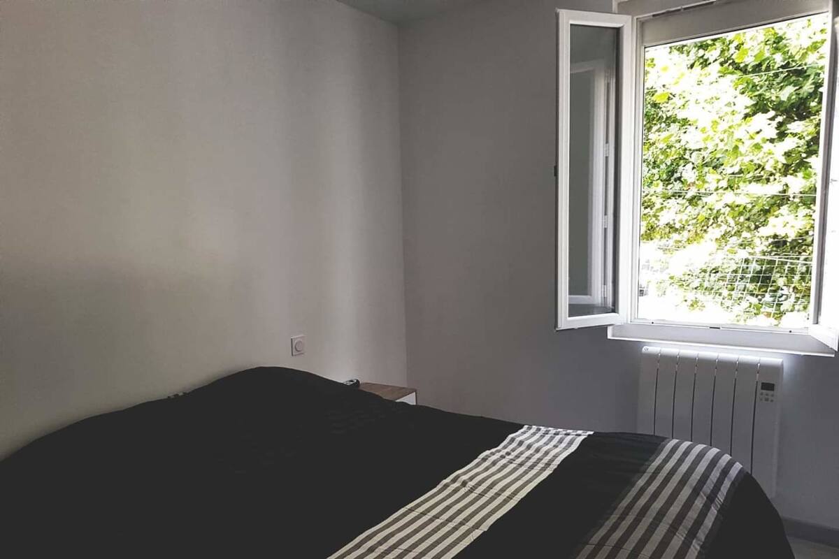 A bedroom with a bed, a window, and a radiator.