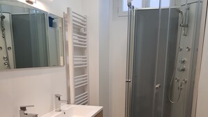 A modern bathroom with a glass-enclosed shower, a double sink vanity, and a large mirror.