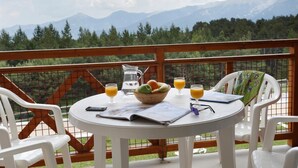 A table with a pitcher, glasses of orange juice, a basket of fruit, and a map on a balcony with a mountain view. - Wifi, 100m from resort center, fitness, swimming pool, terrace, balcony, tv, ski locker, 41m² (Pyrénées 2000)