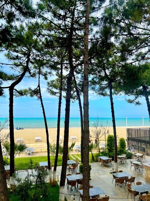 A beachside patio with outdoor seating, overlooking a sandy beach and the ocean. - Hotel Andi (Rrashbull)