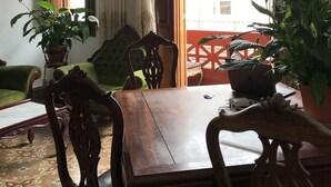 Un comedor con mesa y sillas de madera, plantas en macetas y vistas al exterior.