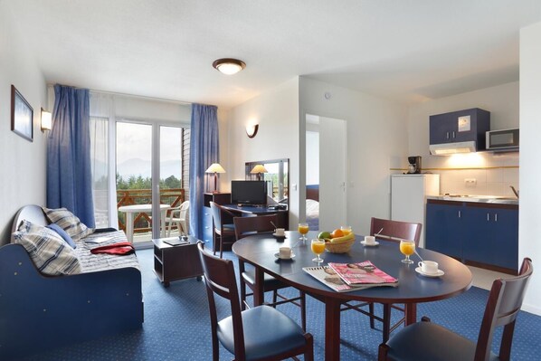 A hotel room with a balcony, a dining area, a kitchenette, and a seating area with a sofa and chairs. - Wifi, 100m from resort center, fitness, swimming pool, terrace, balcony, tv, ski locker, 25m² (Pyrénées 2000)