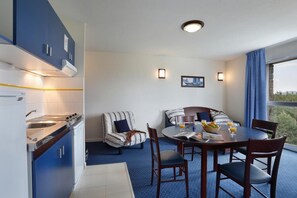 A modern kitchen with a built-in stove and sink, a dining area with a round table and chairs, and a balcony with a view. - Wifi, 100m from resort center, fitness, swimming pool, terrace, balcony, tv, ski locker, 25m² (Pyrénées 2000)